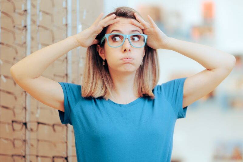 Patient overwhelmed by too many eyeglass frames illustrating how dispensary layout impacts revenue and decision fatigue in optical practices
