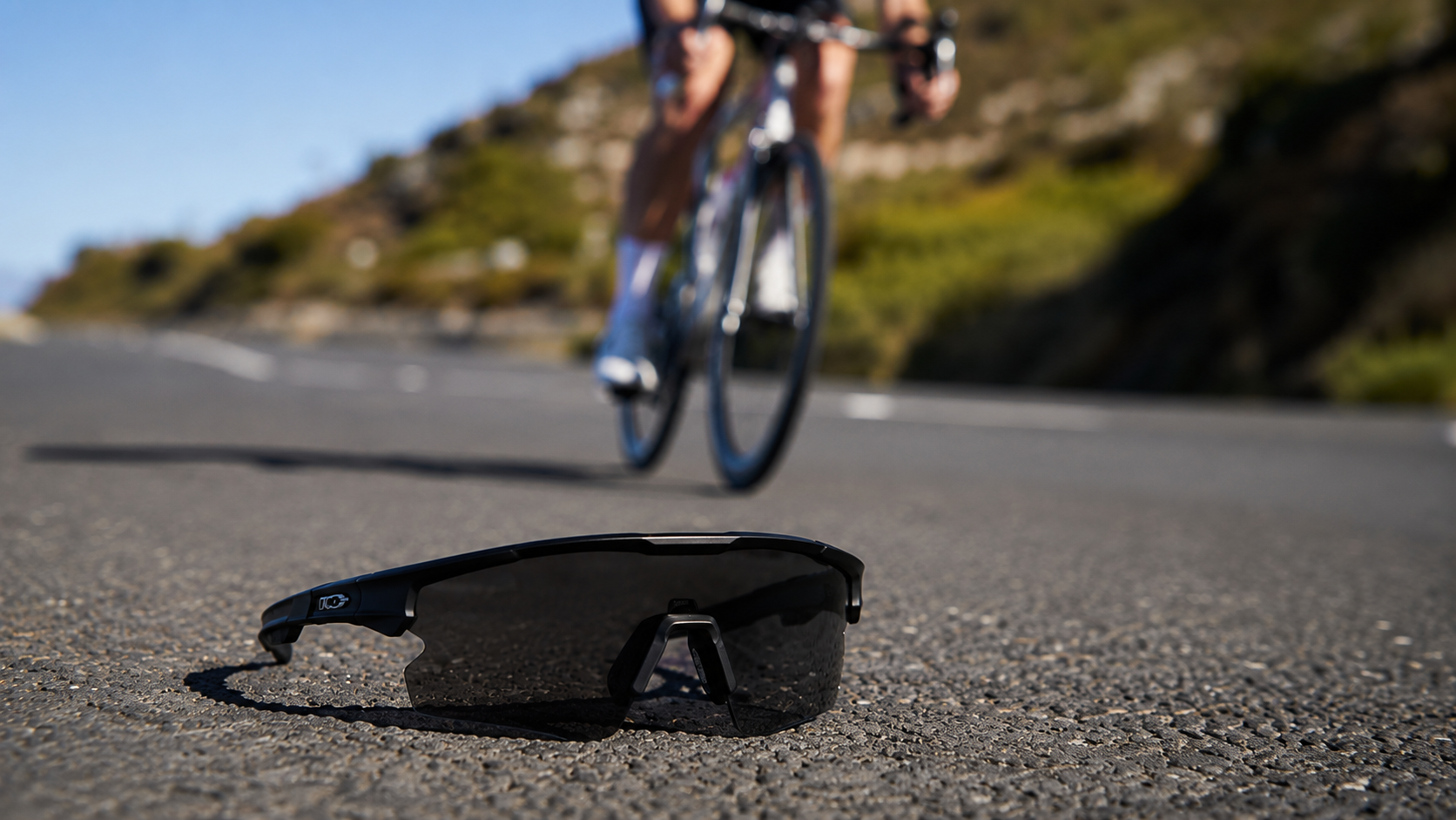 Polycarbonate sport safety glasses on asphalt with cyclist riding in the background
