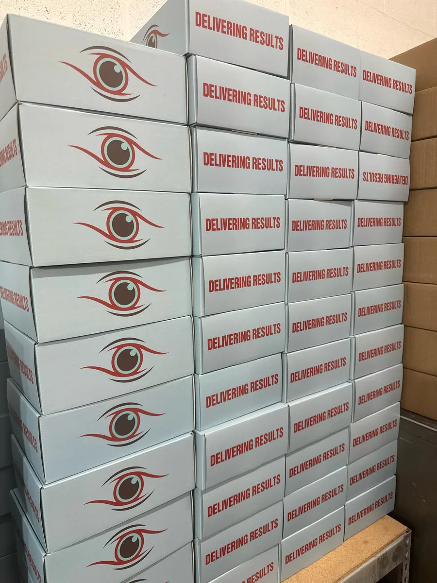 Stack of white Mialab shipping boxes printed with the Delivering Results tagline