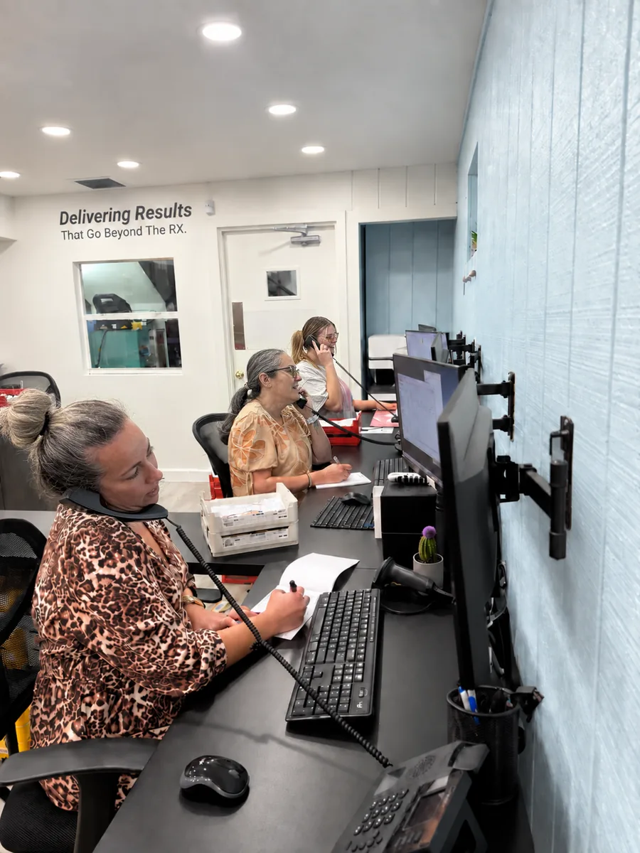 Mialab customer service team members on phone calls at their desks, with a Delivering Results sign on the wall